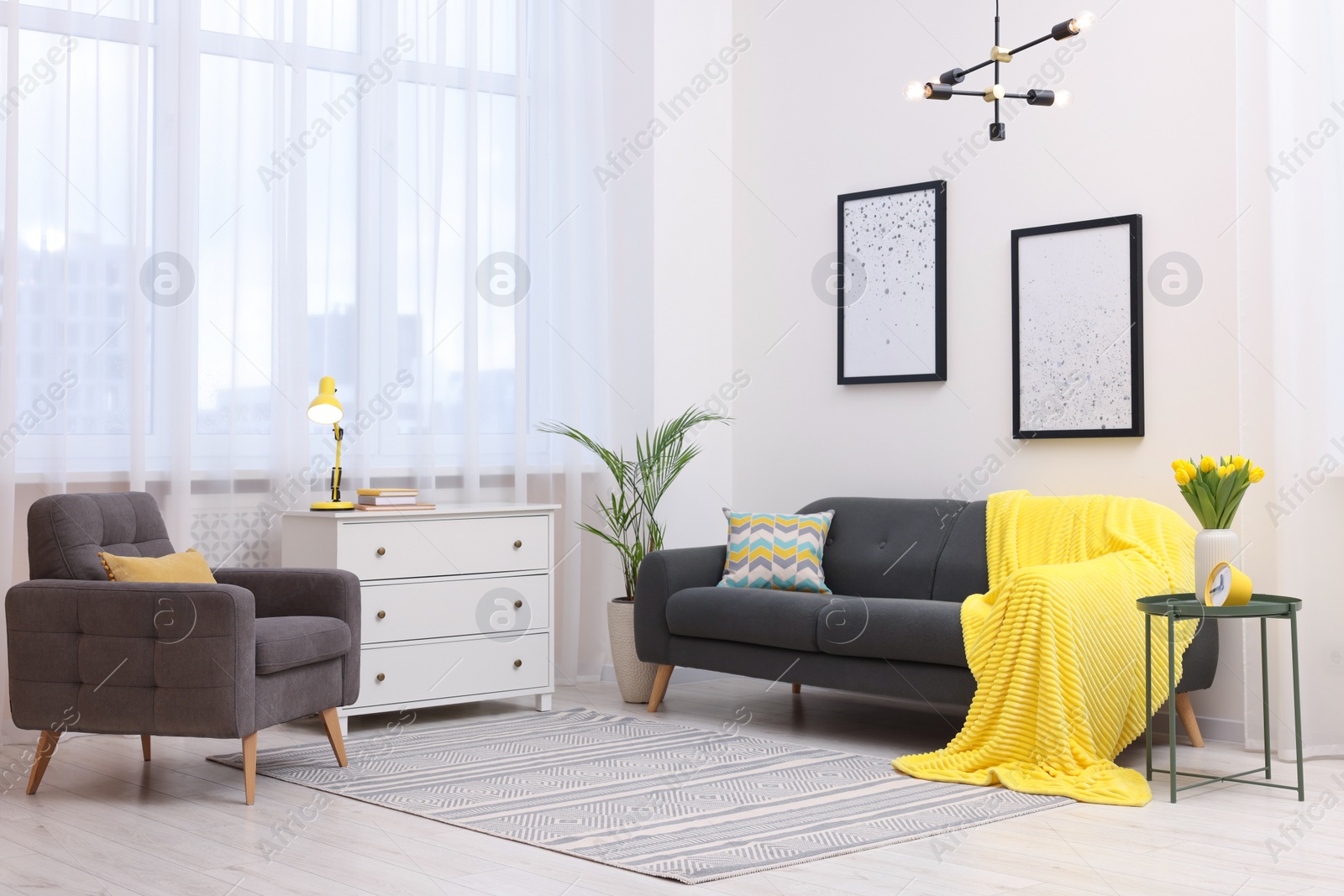 Photo of Spring atmosphere. Stylish living room interior with comfortable furniture and bouquet of beautiful yellow tulips