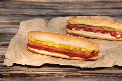 Fresh delicious hot dogs and sauces on wooden surface