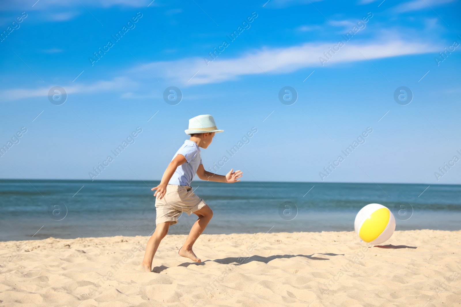 Photo of Cute little boy playing with inflatable ball on sandy beach