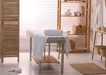 Comfortable massage table with clean towels in spa center