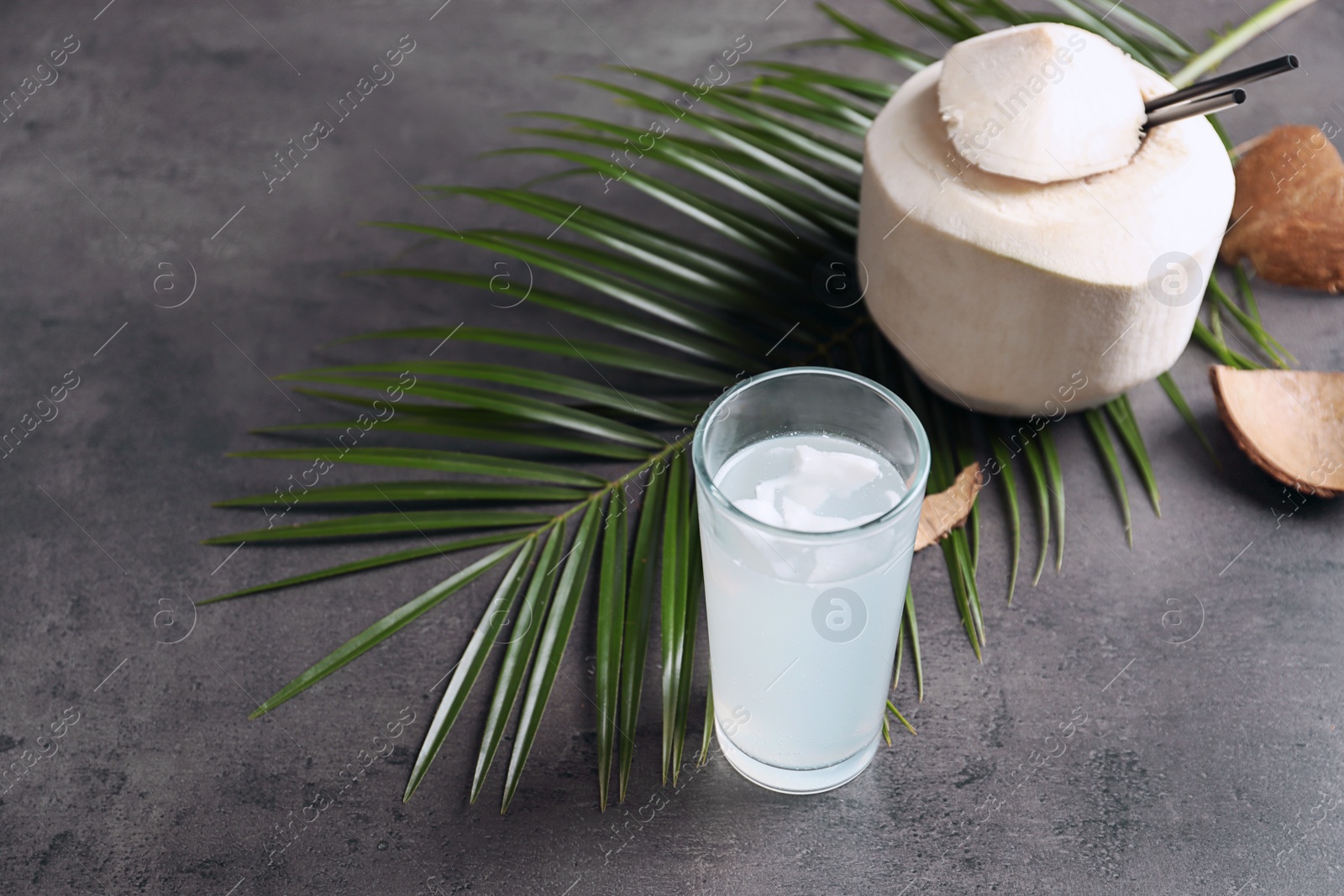 Photo of Glass with fresh coconut water on grey background