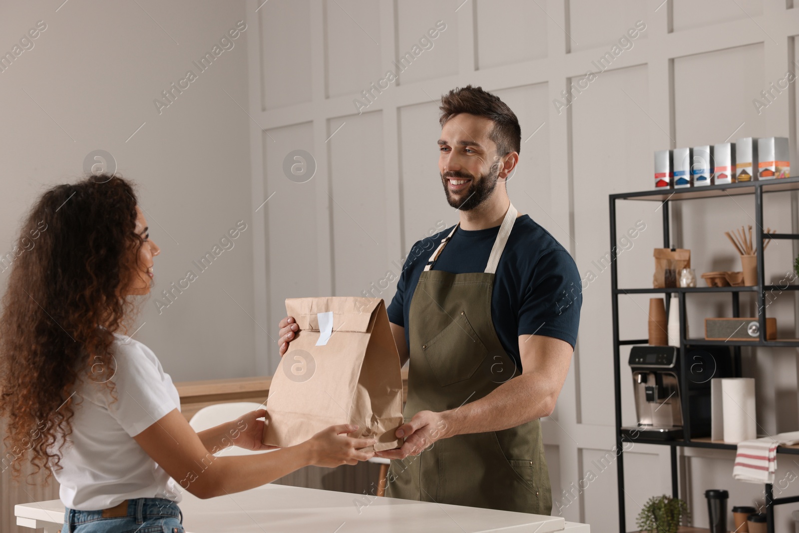 Photo of Worker giving paper bag to customer in cafe