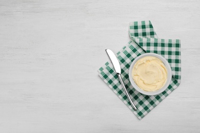 Photo of Bowl with tasty fresh butter and knife on table, top view