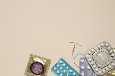 Photo of Contraceptive pills, condoms and intrauterine device on beige background, flat lay with space for text. Different birth control methods
