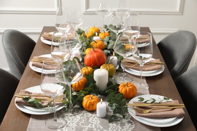 Beautiful autumn table setting. Plates, cutlery, glasses, pumpkins and floral decor