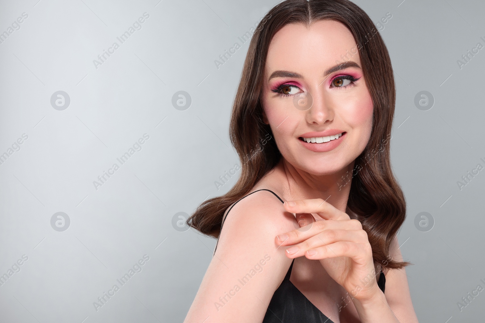 Photo of Portrait of beautiful young woman with makeup and gorgeous hair styling on light grey background. Space for text