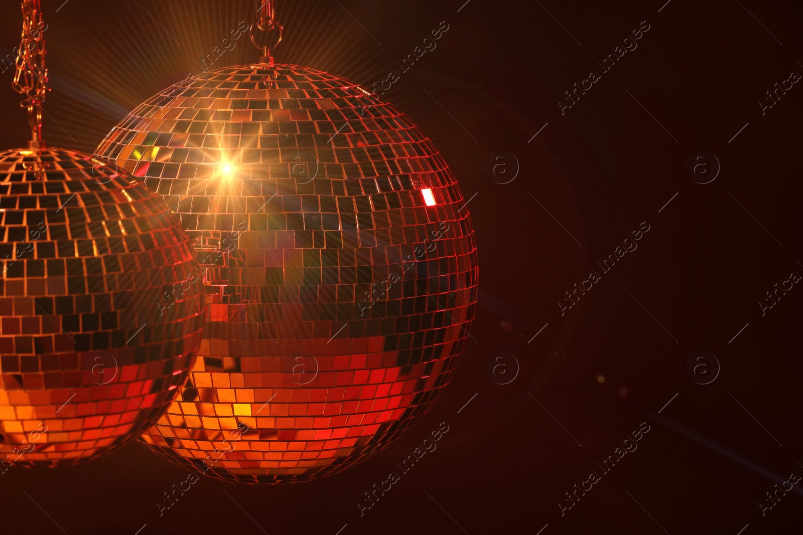 Photo of Shiny bright disco balls under red light, space for text