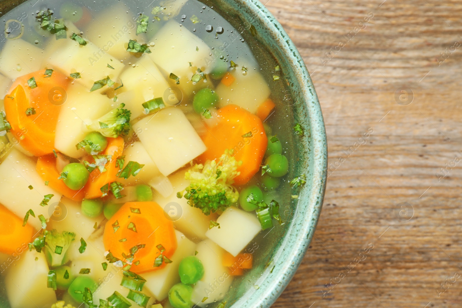 Photo of Bowl of fresh homemade vegetable soup on wooden table, closeup. Space for text