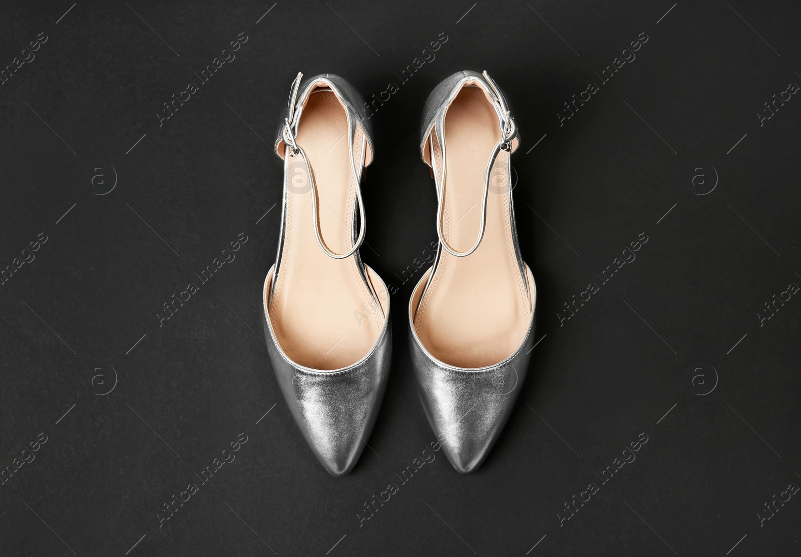 Photo of Pair of female shoes on dark background, top view