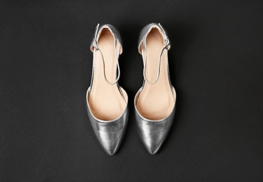 Photo of Pair of female shoes on dark background, top view