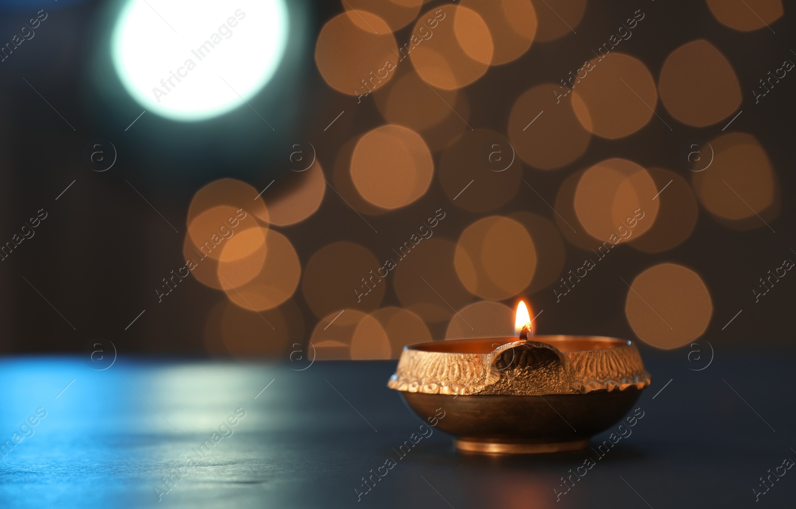 Photo of Lit diya lamp on dark table, space for text. Diwali celebration