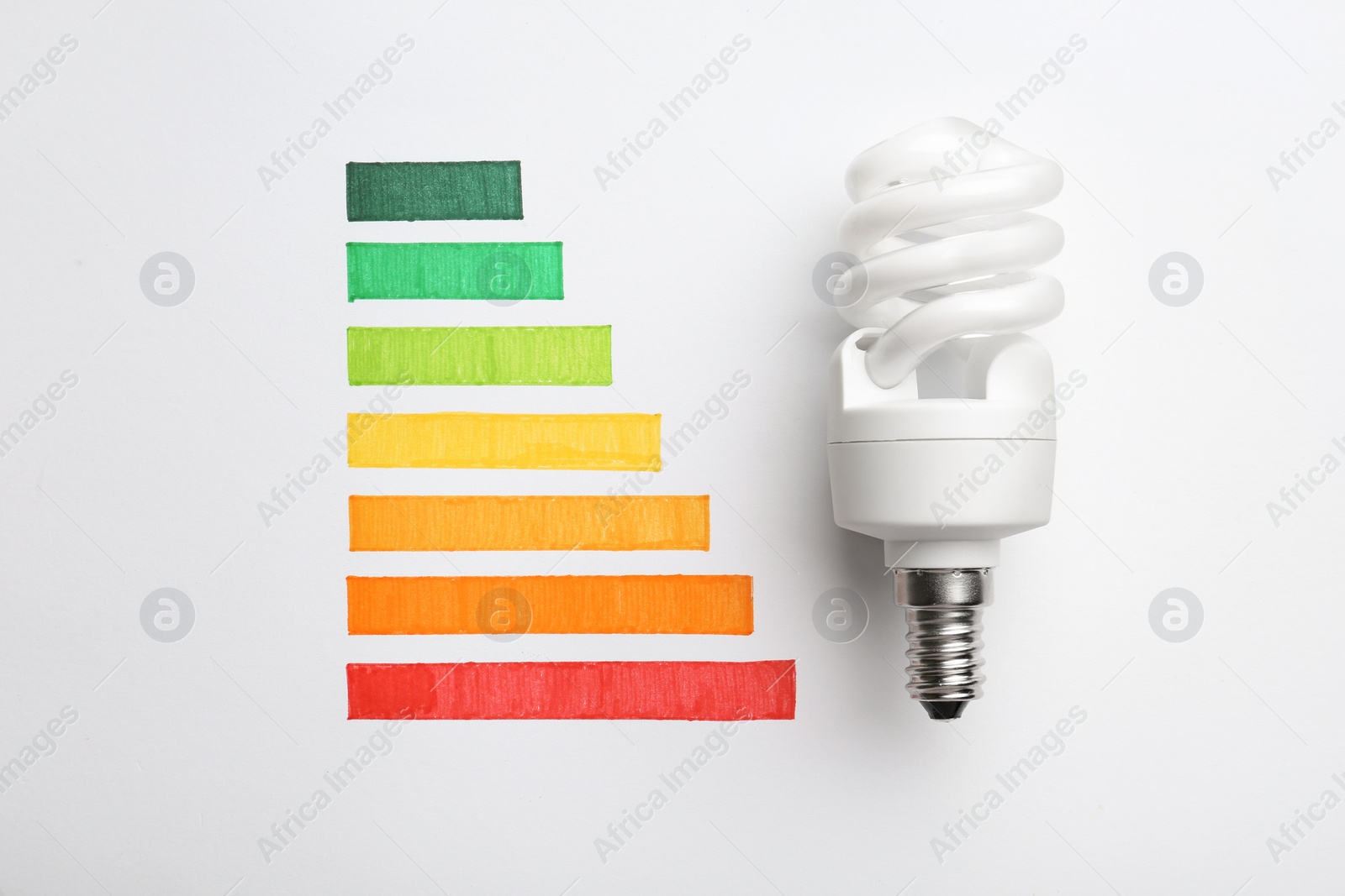 Photo of Flat lay composition with colorful chart and lamp bulb on white background. Energy efficiency concept