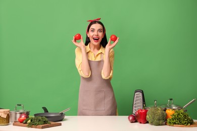 Young housewife with vegetables and different utensils on green background
