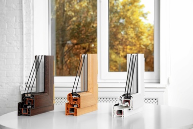 Photo of Samples of modern window profiles on table indoors. Installation service