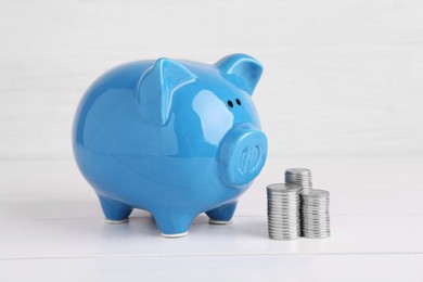 Financial savings. Piggy bank and stacked coins on white wooden table