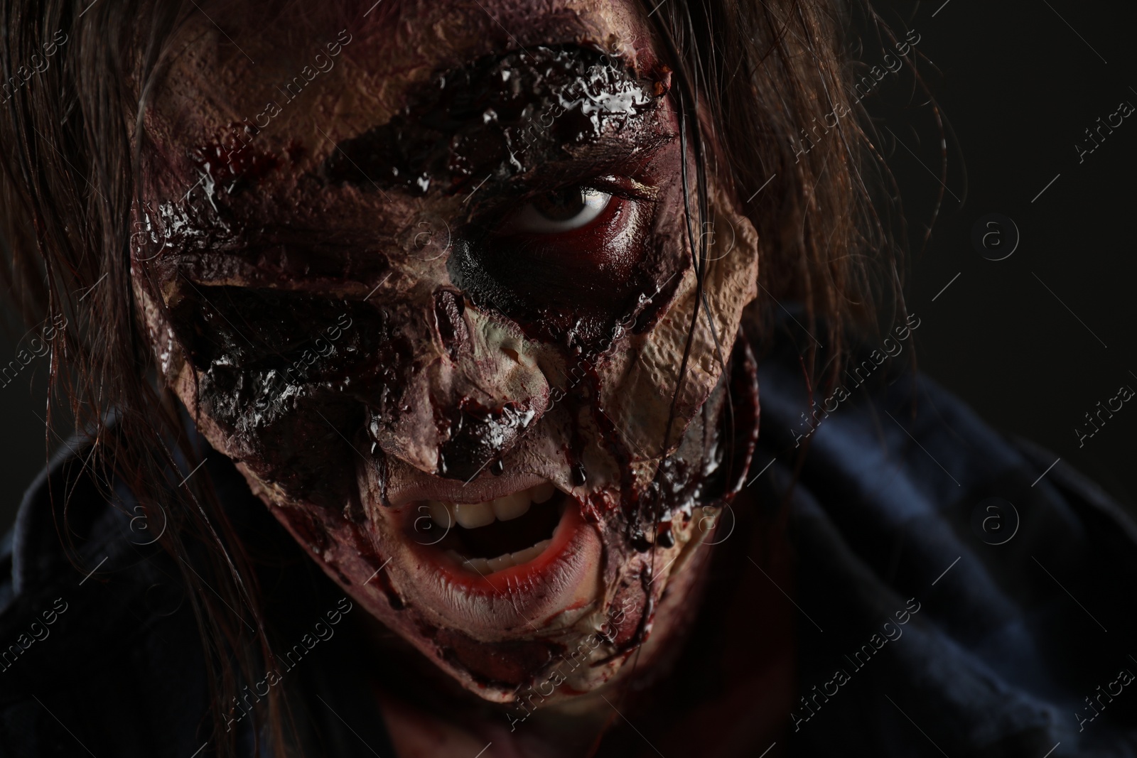 Photo of Scary zombie on dark background, closeup. Halloween monster