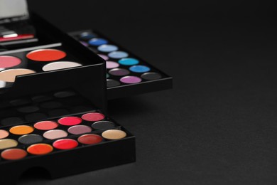 Photo of Makeup case with colorful eyeshadow palette on black background, space for text