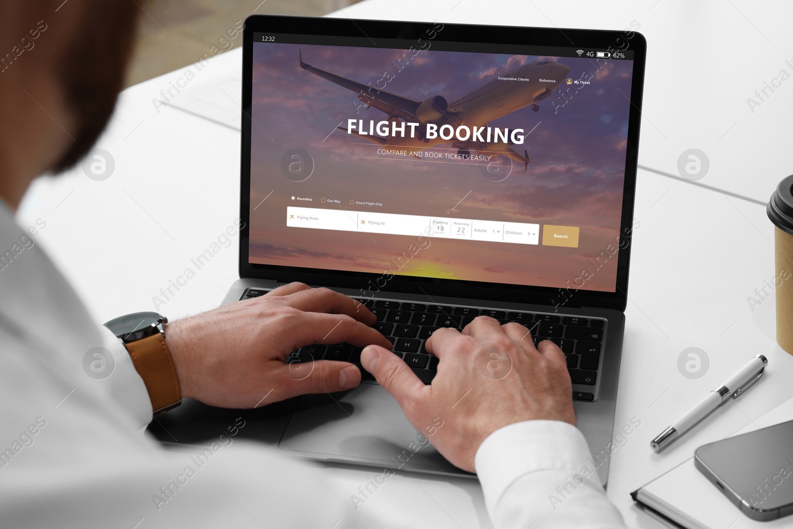 Image of Man using laptop to book flight at white table, closeup