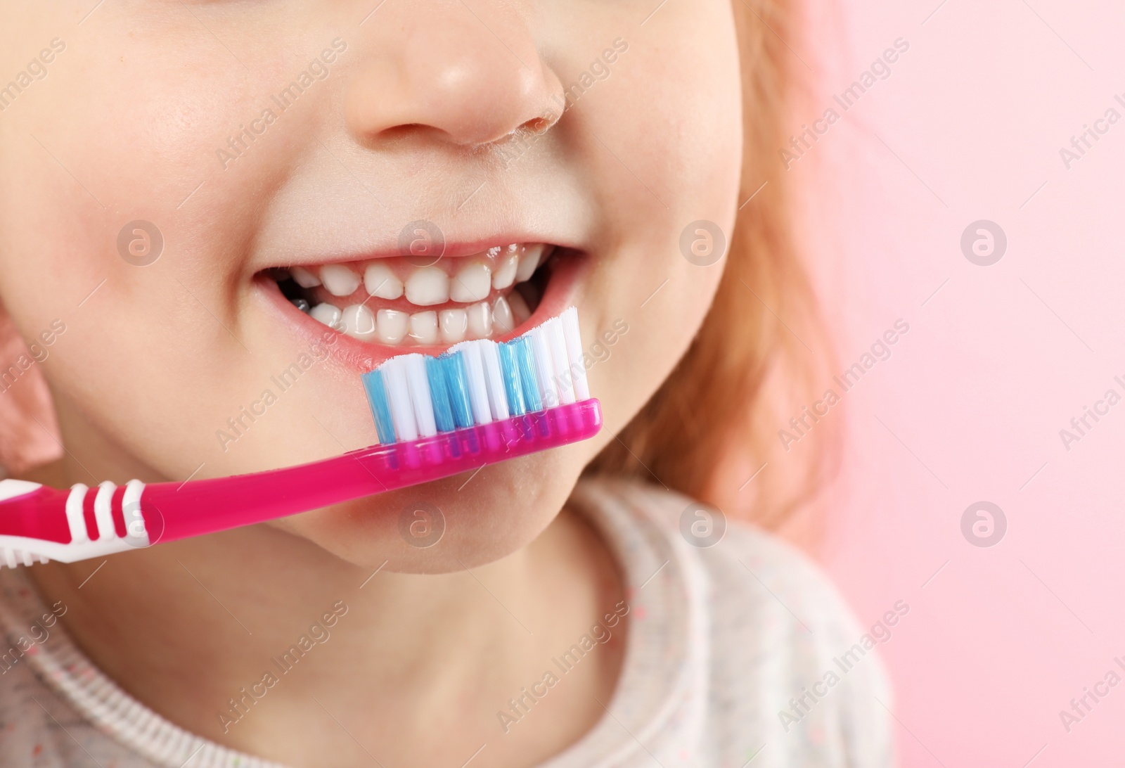 Photo of Little girl brushing teeth on color background, closeup