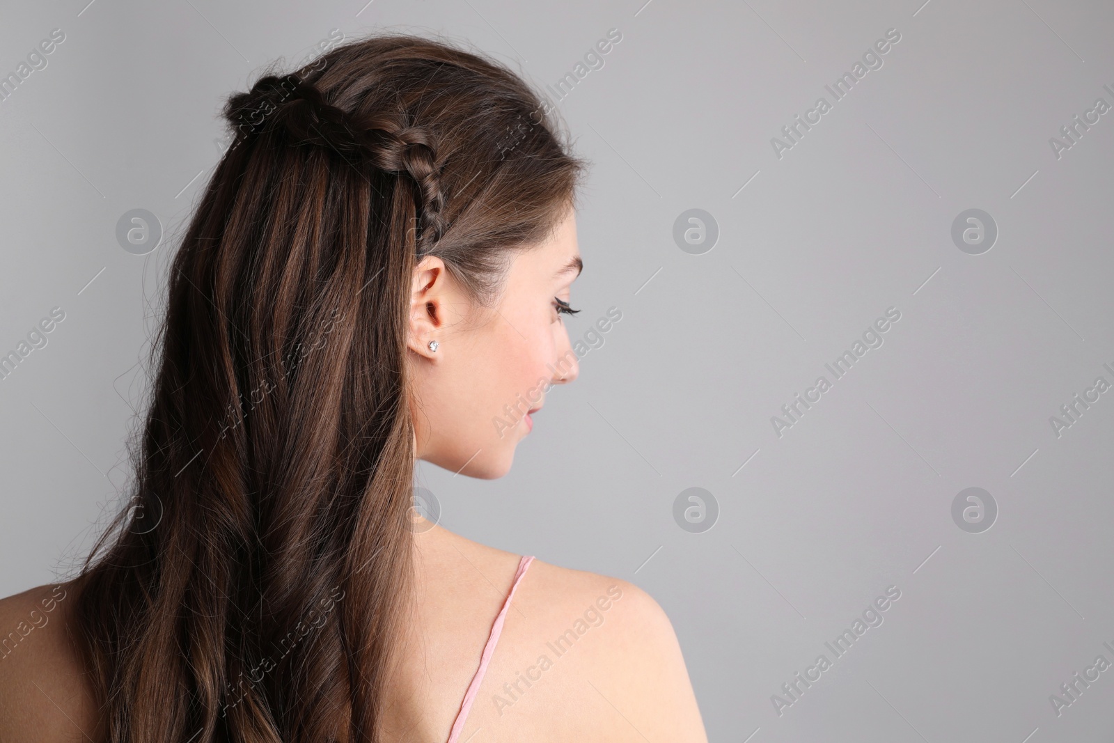Photo of Woman with braided hair on light grey background, back view. Space for text