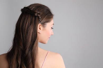 Woman with braided hair on light grey background, back view. Space for text