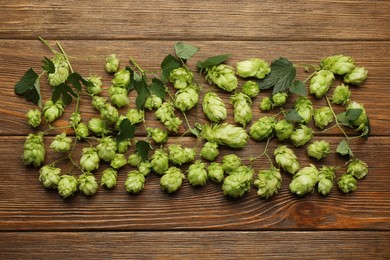 Branches of fresh green hops on wooden table, flat lay