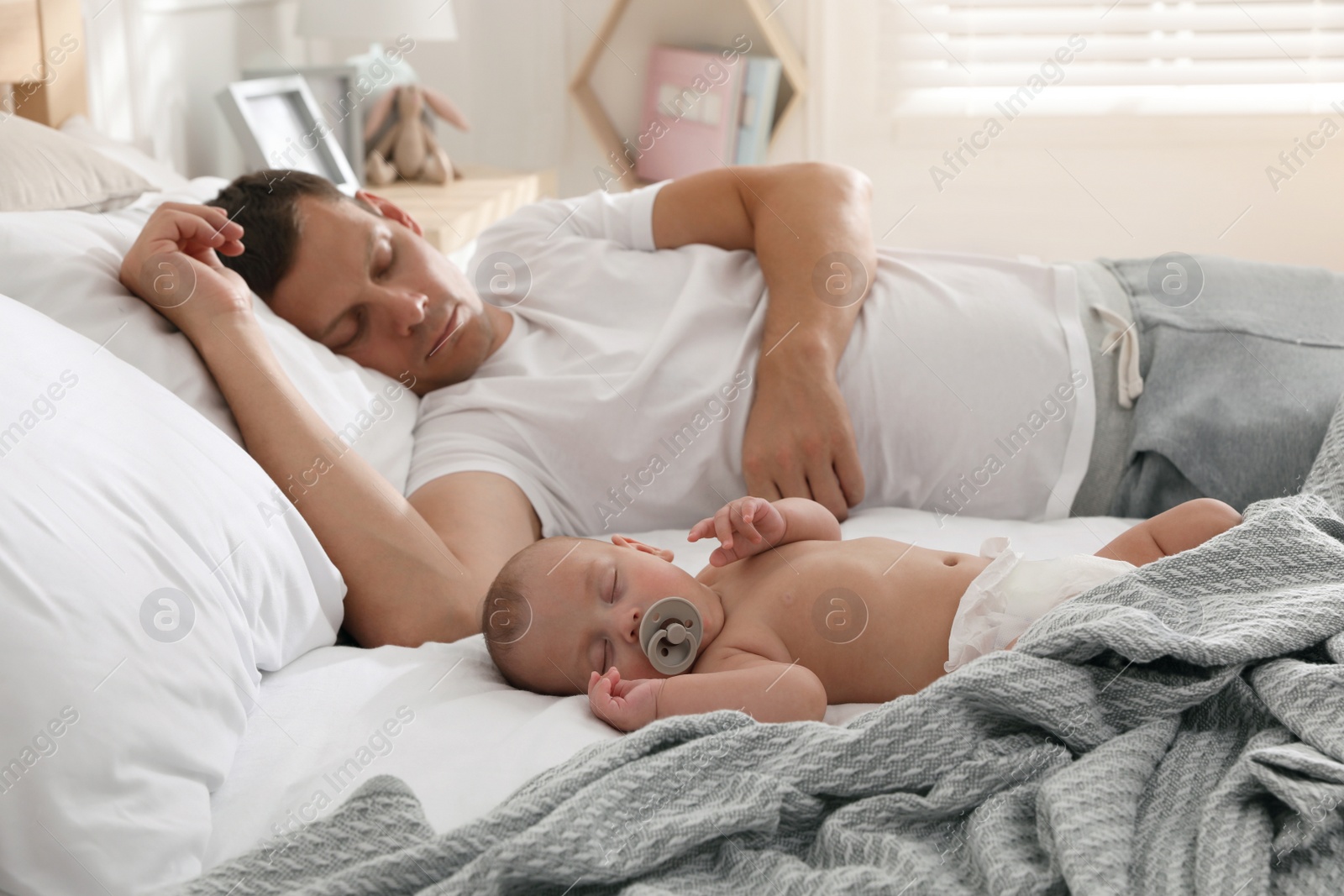 Photo of Father with his cute baby sleeping in bed at home