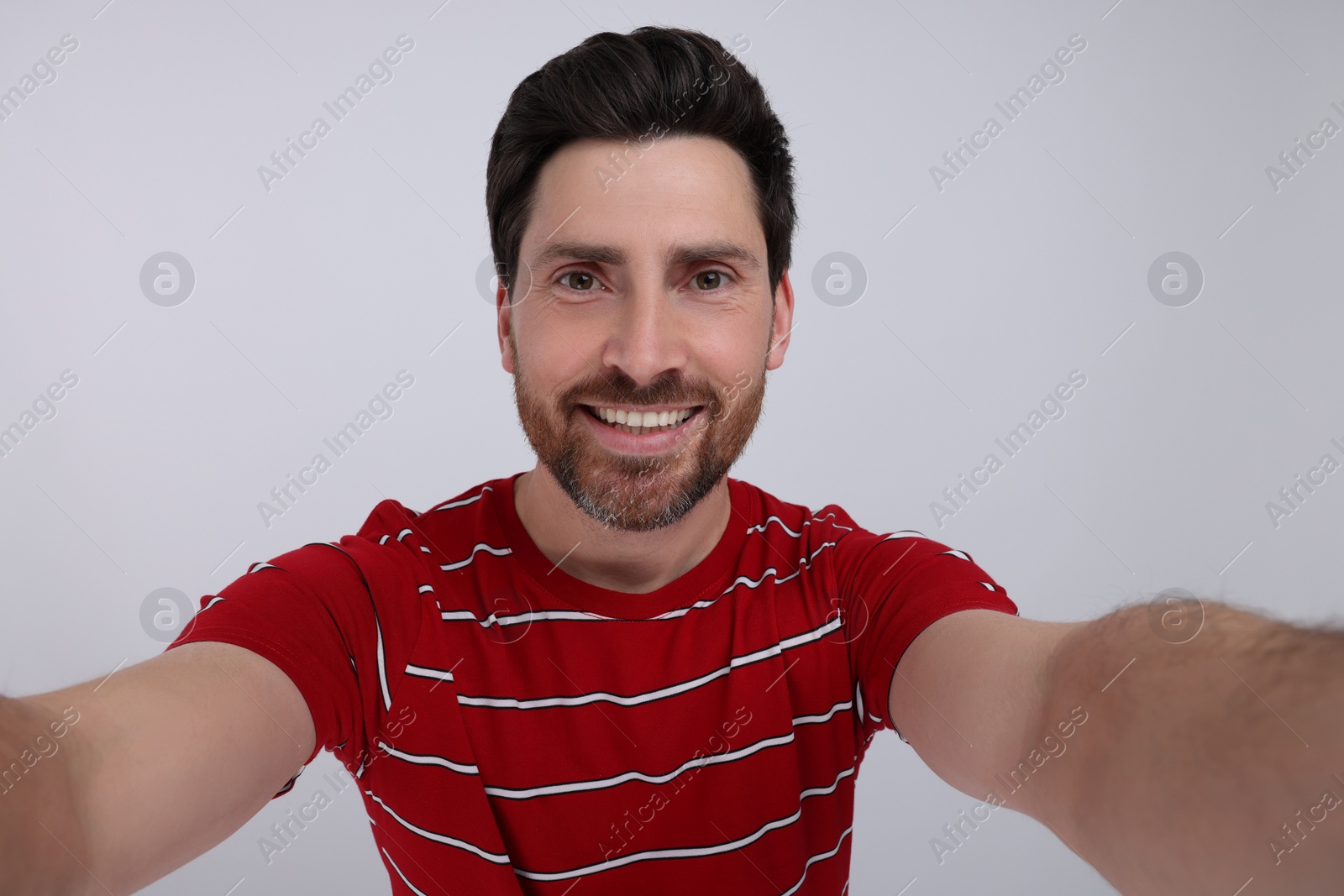 Photo of Smiling man taking selfie on white background