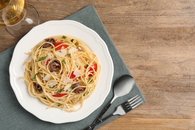 Photo of Delicious pasta with anchovies, tomatoes and parmesan cheese served on wooden table, flat lay. Space for text