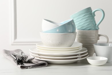 Photo of Beautiful ceramic dishware, cups and cutlery on white marble table