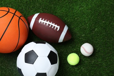 Photo of Set of different sport balls on green grass, flat lay