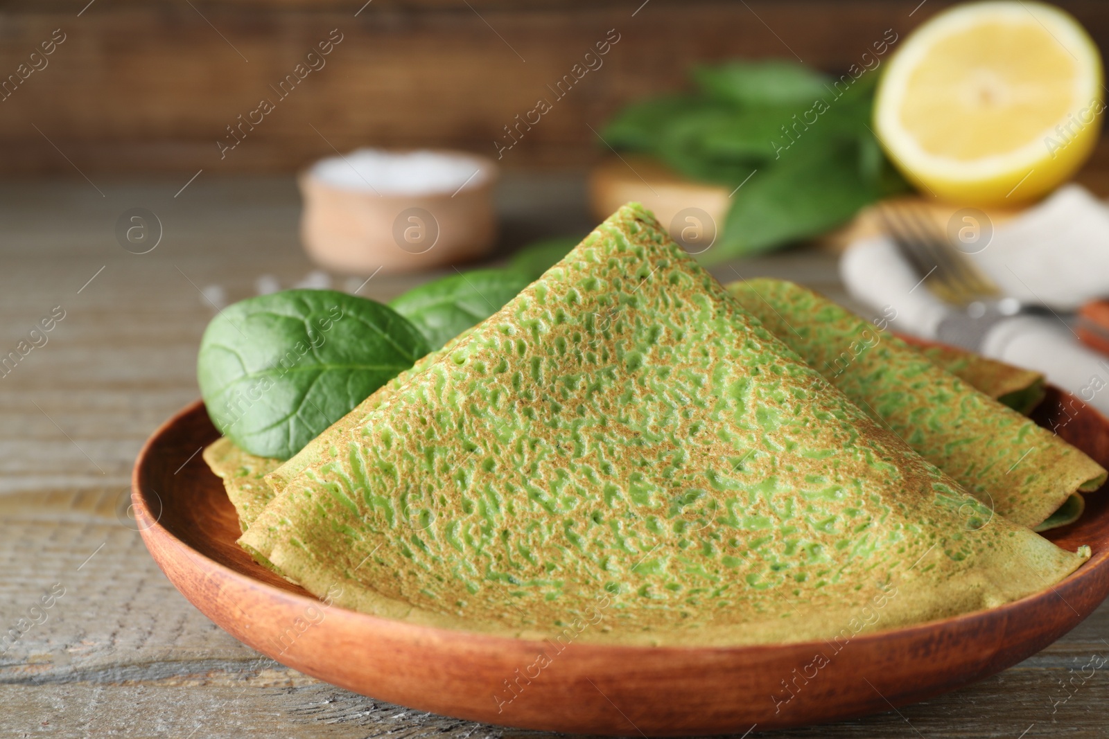 Photo of Delicious spinach crepes served on wooden table