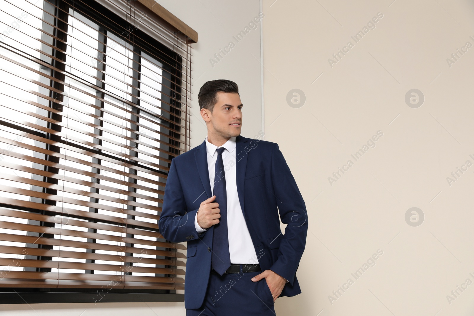 Photo of Portrait of confident businessman in suit at window indoors