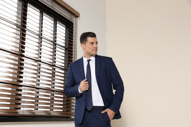 Portrait of confident businessman in suit at window indoors