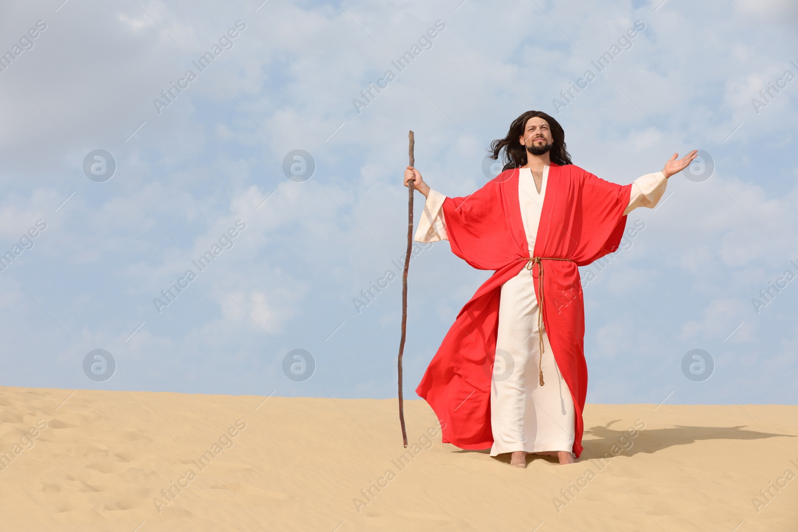 Photo of Jesus Christ walking with stick in desert. Space for text