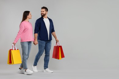 Photo of Happy couple with shopping bags on grey background. Space for text