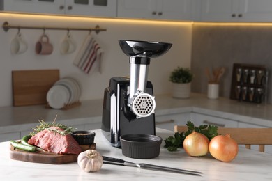 Photo of Electric meat grinder with beef mince and products on white marble table in kitchen