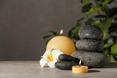 Photo of Composition with candles and spa stones on grey table. Space for text