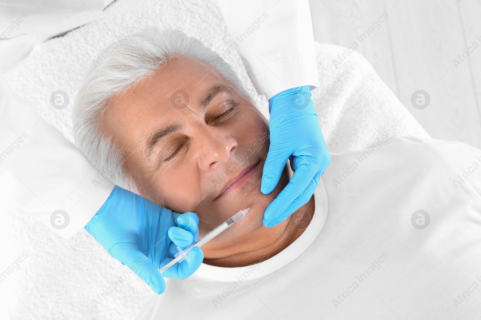 Photo of Senior man getting facial injection in clinic. Cosmetic surgery concept