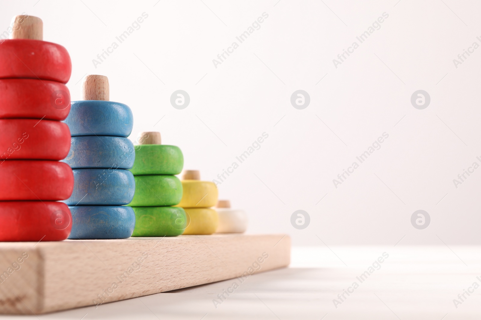 Photo of Motor skills development. Stacking and counting game pieces on white table, closeup. Space for text