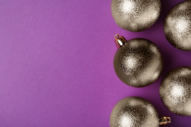 Photo of Many shiny Christmas balls on purple background, flat lay with space for text