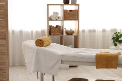 Comfortable massage table with clean towels in spa center