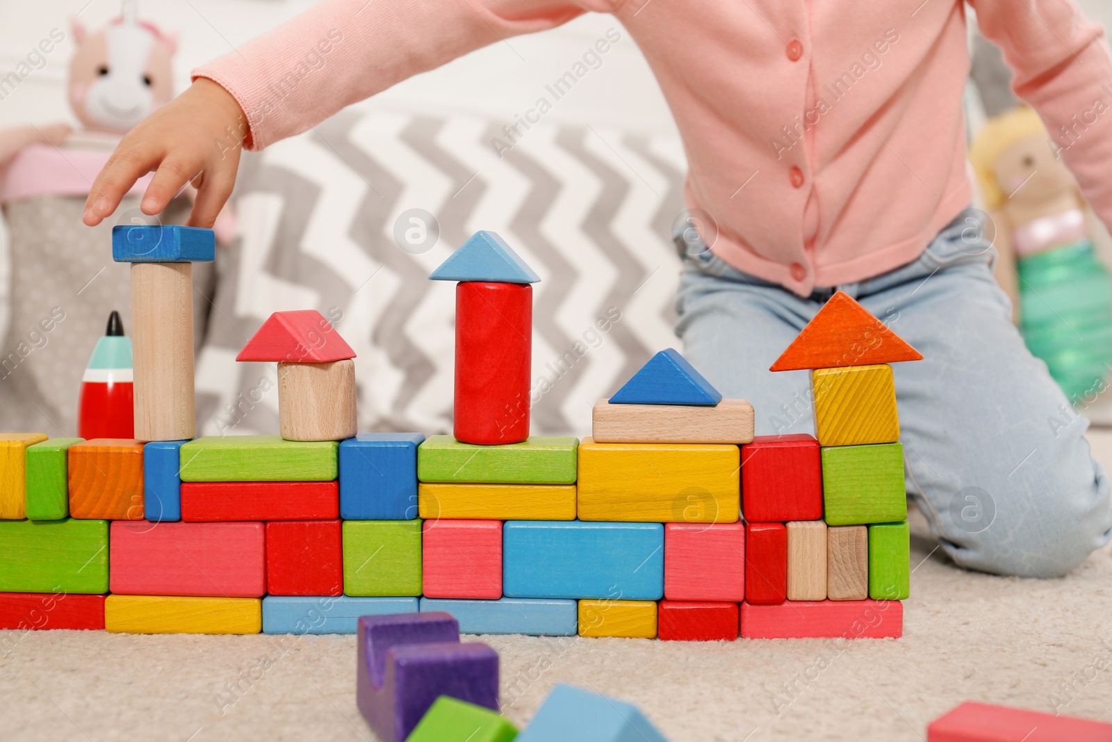 Photo of Cute little girl playing with colorful building blocks at home, closeup