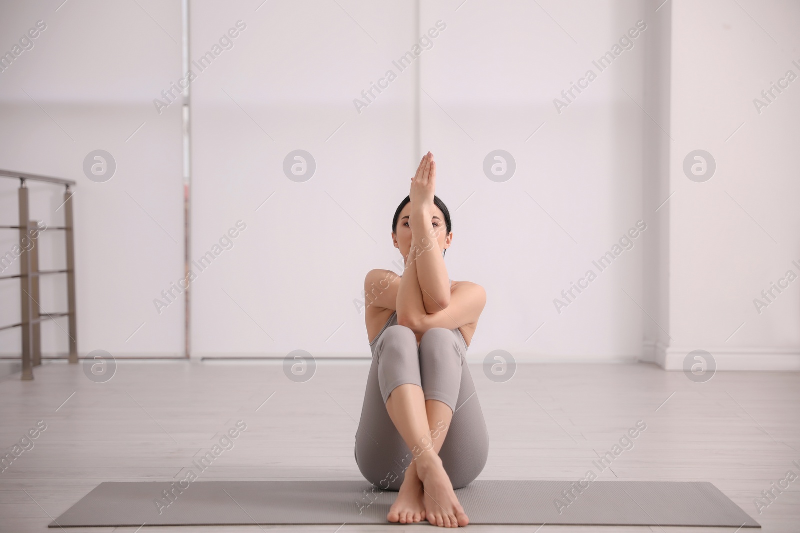 Photo of Young woman practicing eagle asana in yoga studio. Garudasana pose