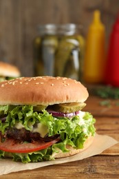 Photo of Delicious burger with beef patty and lettuce on wooden table, closeup