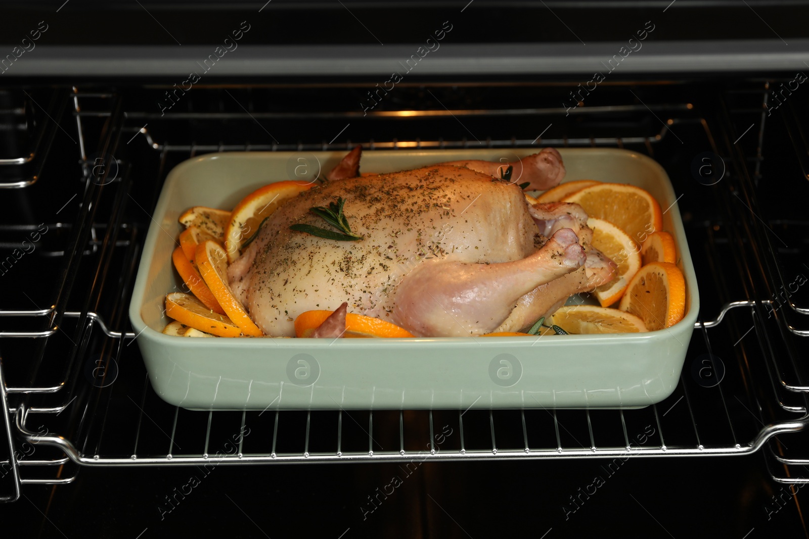 Photo of Chicken with orange slices baking in oven