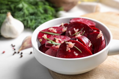 Photo of Raw beetroot slices, garlic and rosemary in bowl on white table, closeup