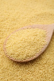 Photo of Wooden spoon and uncooked organic couscous as background, closeup