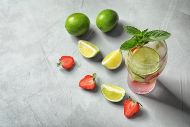 Photo of Natural lemonade with lime and strawberries in glass on light background