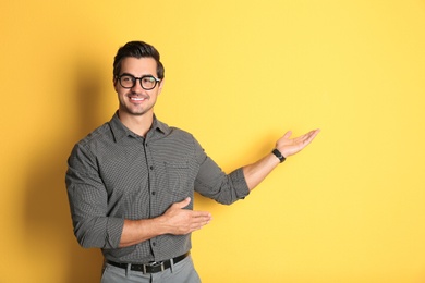 Young male teacher with glasses on yellow background. Space for text